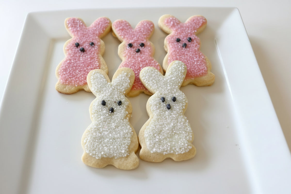 Decorative cookies shaped like bunnies and a bow tie on a white plate.
